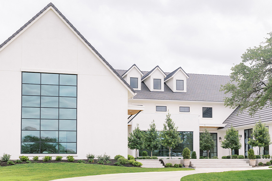 Front exterior of The Arlo showing the gabled great room, dormers, and a tree-lined entry walk