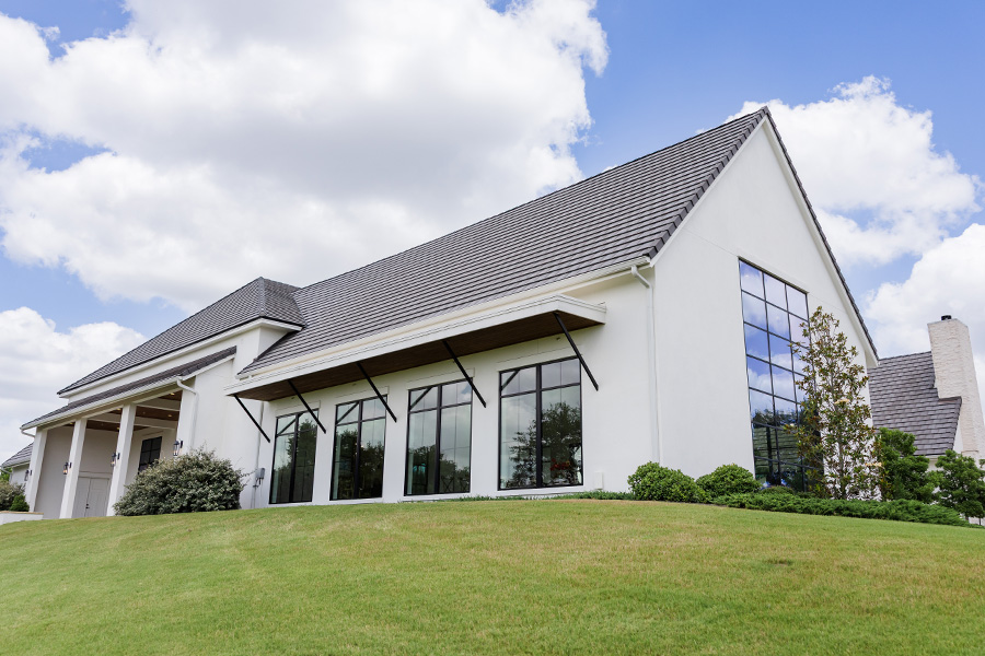 Side view of The Arlo with sloped rooflines, black-framed windows, and an open event lawn